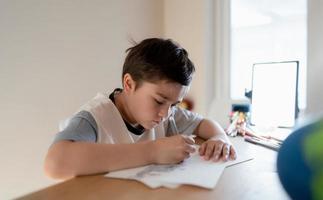 School kid using grey colour pen drawing or sketching on paper,Portrait  boy siting on table doing homework in living room,Child enjoy art and craft activity at home on weekend,Education concept photo