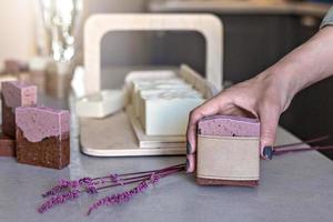 A soap-maker girl holds a piece of freshly brewed handmade soap in her hands.Cooking process.Home spa.Small business. photo