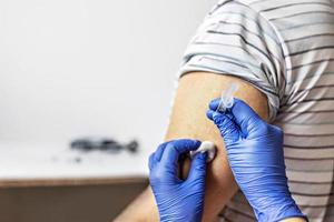 A doctor vaccinates a man against coronavirus at a clinic. Close-up. The concept of vaccination, immunization, prevention against Covid-19. photo