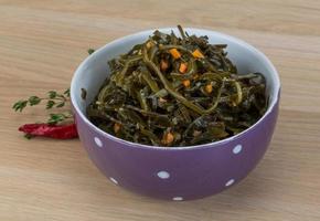 Laminaria salad in a bowl on wooden background photo