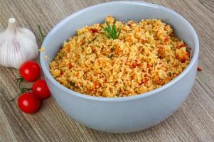 Couscous in a bowl on wooden background photo