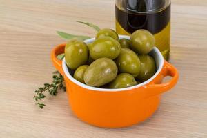 Green olives in a bowl on wooden background photo