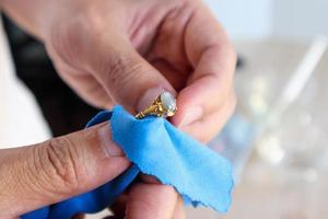 Jeweller hand polishing and cleaning gold jewelry ring with micro fiber fabric photo