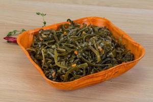 Laminaria salad in a bowl on wooden background photo