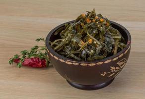 Laminaria salad in a bowl on wooden background photo