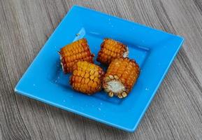 Grilled corn on the plate and wooden background photo