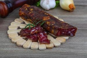 Salami sausage on wooden board and wooden background photo