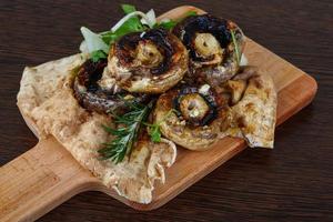 Baked champignons on wooden board and wooden background photo