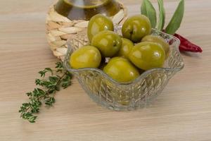 Green olives in a bowl on wooden background photo