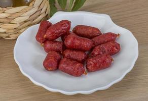 Mini salami on the plate and wooden background photo