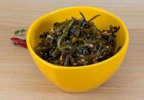 Laminaria salad in a bowl on wooden background photo