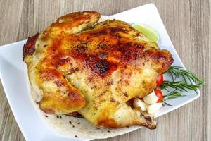 pollo a la parrilla en el plato y fondo de madera foto