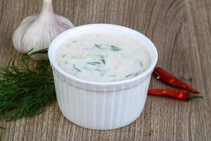 Tzatziki in a bowl on wooden background photo