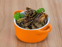 Grilled artishokes in a bowl on wooden background photo