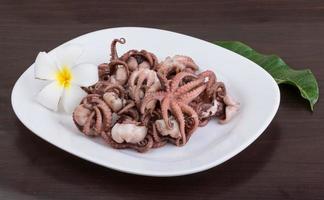 Boiled octopus on the plate and wooden background photo