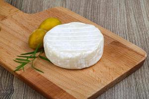 Brie cheese on wooden board and wooden background photo