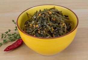 Laminaria salad in a bowl on wooden background photo