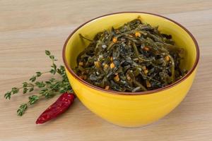 Laminaria salad in a bowl on wooden background photo