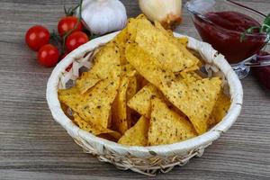 Nachos in a basket on wooden background photo