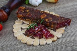 Salami sausage on wooden board and wooden background photo