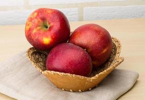 Red apples in a basket on wooden background photo