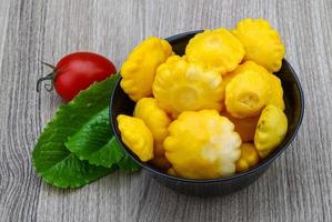 Pickled patissons in a bowl on wooden background photo