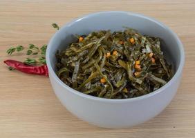 Laminaria salad in a bowl on wooden background photo