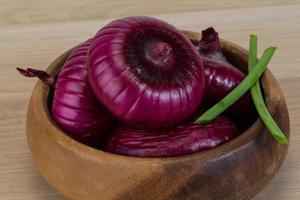 Violet onion in a bowl on wooden background photo