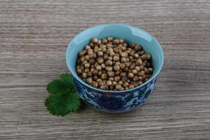 semillas de cilantro en un recipiente sobre fondo de madera foto