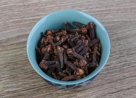 Cloves seeds in a bowl on wooden background photo