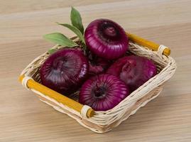 Violet onion in a basket on wooden background photo