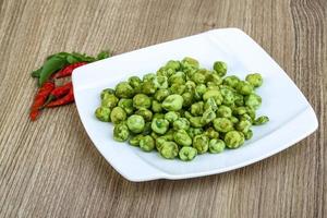 Wasabi peas on the plate and wooden background photo