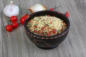 Raw couscous in a bowl on wooden background photo