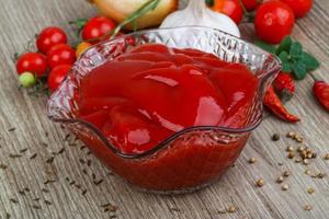 ketchup de tomate en un recipiente sobre fondo de madera foto