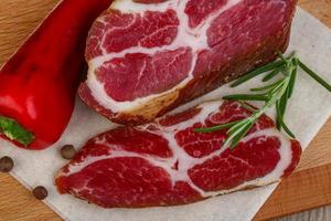 Smoked bacon on wooden board and wooden background photo