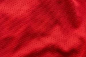 camiseta de fútbol de ropa deportiva de tela roja con fondo de textura de malla de aire foto