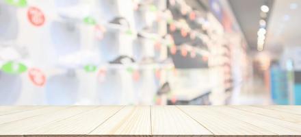 Wood table top with sneakers showcase on shelves in sport shoes store window display abstract blurred background photo