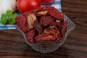 Dried tomtoes in a bowl on wooden background photo