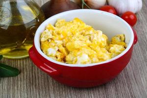 Scrambled eggs in a bowl on wooden background photo