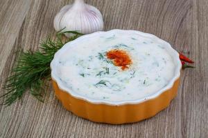 Tzatziki in a bowl on wooden background photo