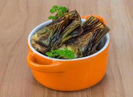 Grilled artishokes in a bowl on wooden background photo