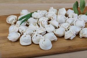 Raw dumplings on wooden board and wooden background photo