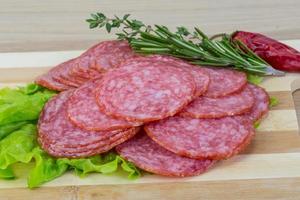 Sliced salami on wooden board and wooden background photo