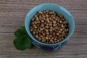 semillas de cilantro en un recipiente sobre fondo de madera foto