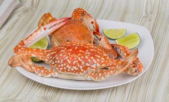 Boiled crabs on the plate and wooden background photo