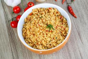 Couscous in a bowl on wooden background photo