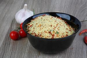 Raw couscous in a bowl on wooden background photo