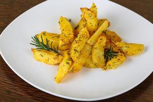 Roasted potato on the plate and wooden background photo