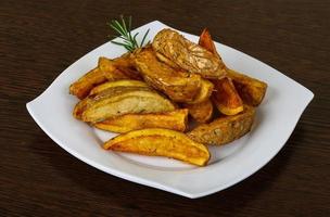 Roasted potato on the plate and wooden background photo