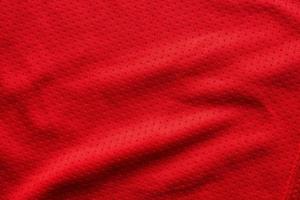 camiseta de fútbol de ropa deportiva de tela roja con fondo de textura de malla de aire foto